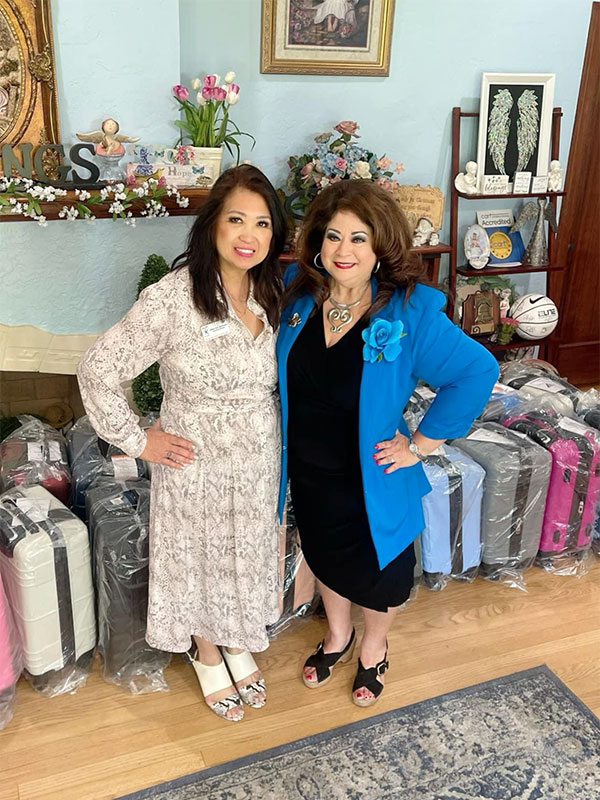 Image of two women standing in a room with the suitcase CharityRx donates to their organizations