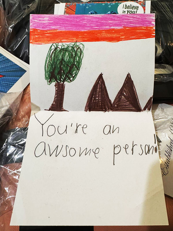 Image of a notecard with a drawing of mountains and trees, and the words "You're an awesome person!"