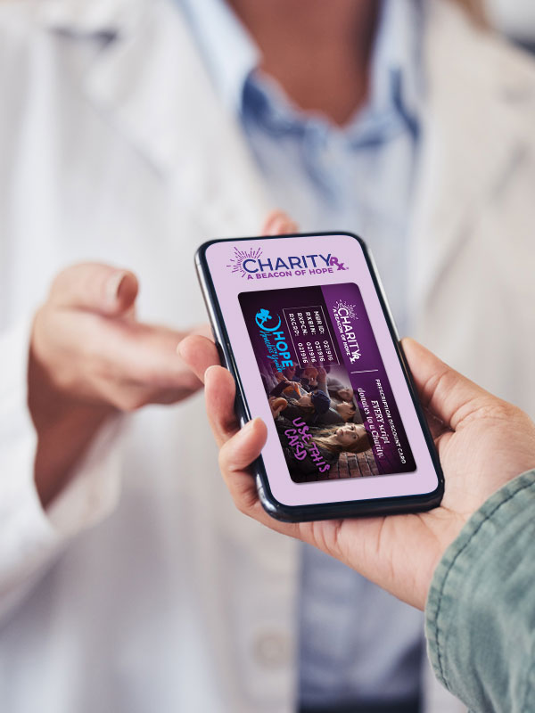 Image of a customer handing a smart phone to a pharmacist with the CharityRx prescription discount card image on the screen