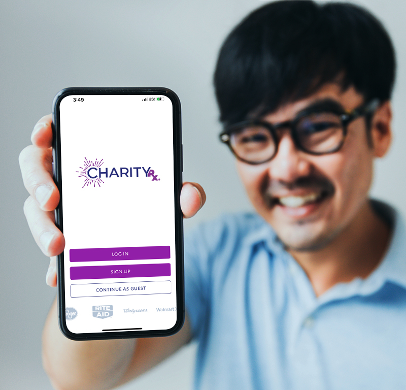 A smiling young man holds his smart phone up, showing the screen with the CharityRx app login screen.