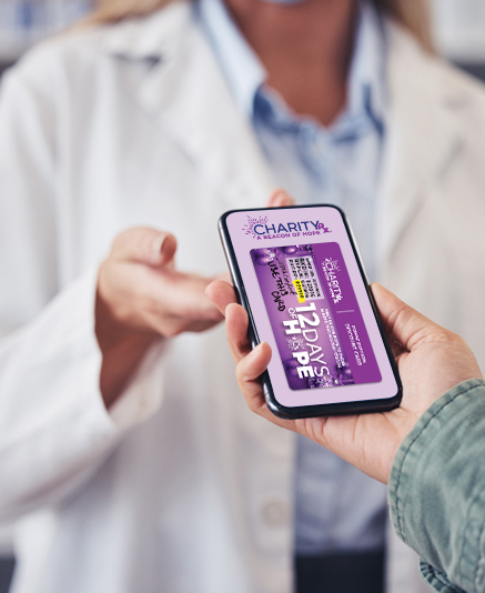 A pharmacy customer hands their smart phone to the pharmacist. On the screen is a CharityRx prescription discount card.