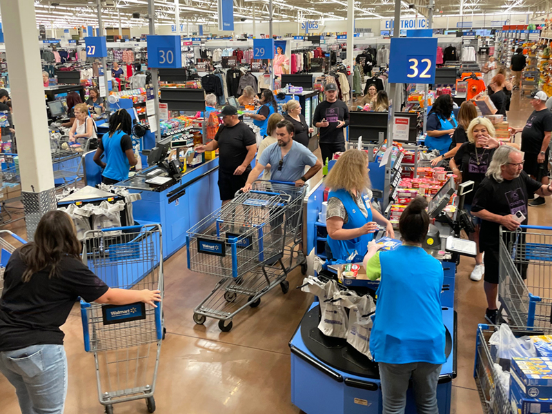 CharityRx team members stand in a crowded checkout area with carts full of food and clothing to donate to Project 150.