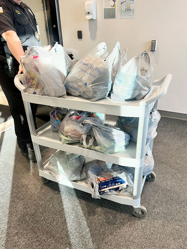 A security guard at the Christmas Box House pulls a cart loaded with plastic bags full of clothing, art supplies, and hygiene products.