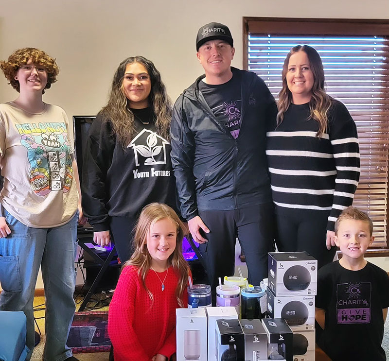 A father, mother, and two young children pose behind their donations with volunteers from Youth Futures.