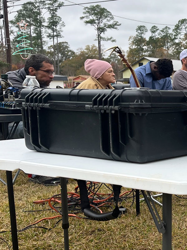 Two men and a woman sit behind a table with audio equipment on it.